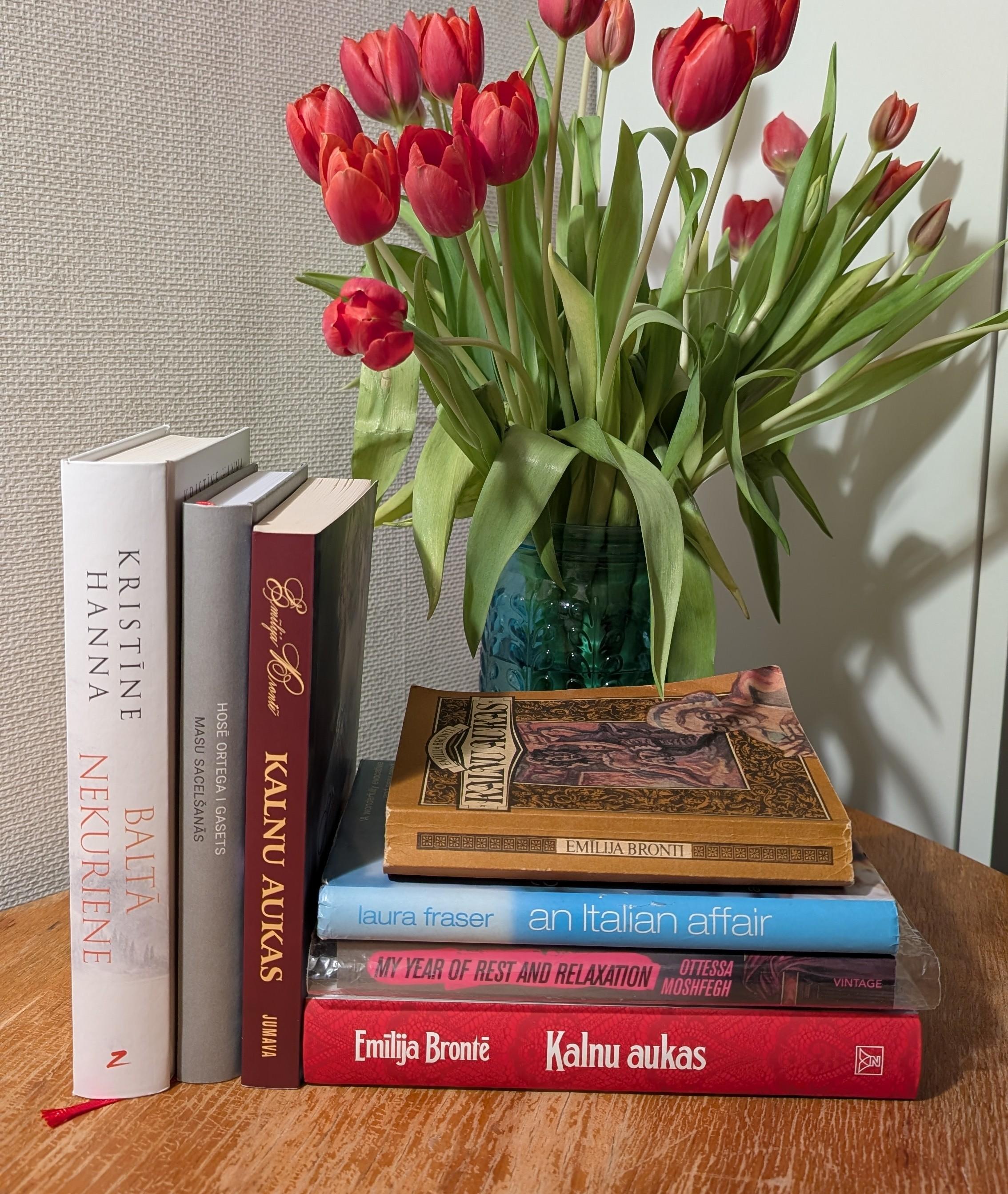 Uz galda grāmatas un vāzē tulpes.